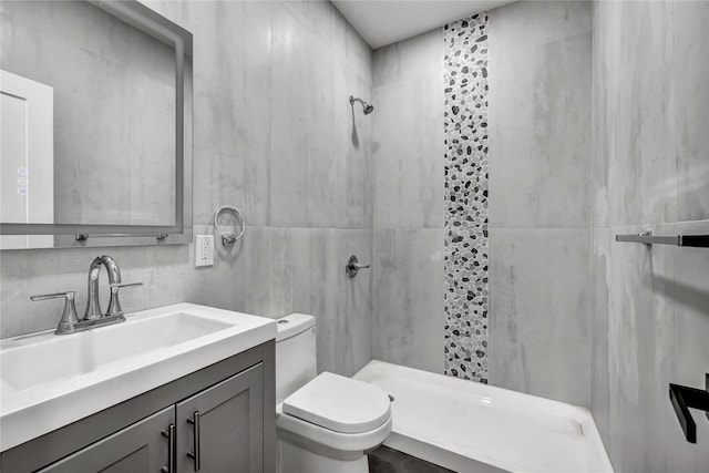 full bath with tile walls, toilet, a tile shower, and vanity