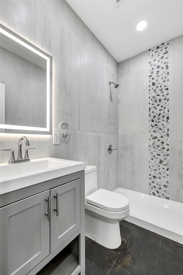 full bathroom with tile walls, a shower stall, toilet, vanity, and tile patterned flooring