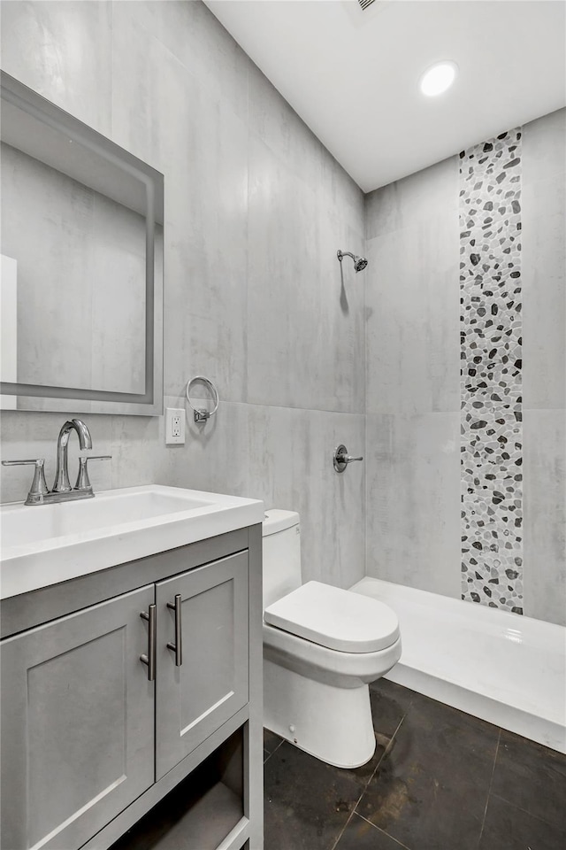 bathroom featuring toilet, vanity, tile walls, and a shower stall