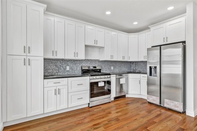 kitchen featuring a sink, dark countertops, light wood-style floors, and appliances with stainless steel finishes