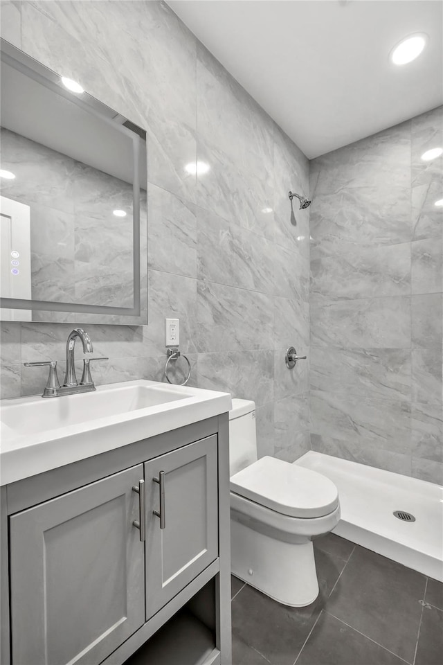 full bath with a stall shower, tile patterned floors, toilet, vanity, and tile walls