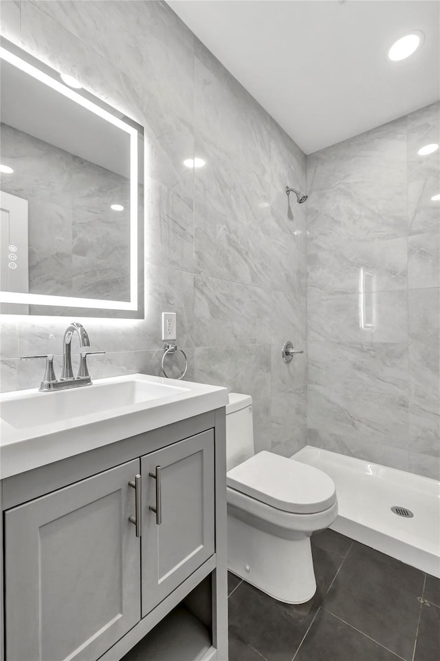 full bathroom with tile walls, a shower stall, toilet, tile patterned floors, and vanity
