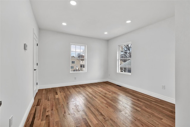 unfurnished room featuring a wealth of natural light, recessed lighting, wood finished floors, and baseboards