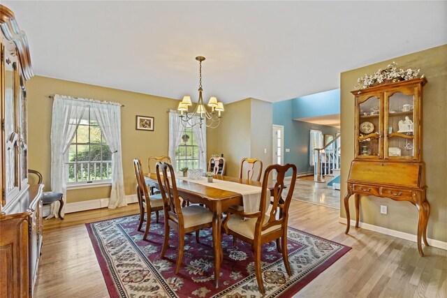 dining space with baseboards, light wood finished floors, stairs, and a chandelier