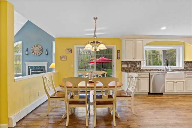 dining area with a premium fireplace, light wood-style floors, a chandelier, and a baseboard radiator
