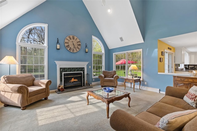 carpeted living area with high vaulted ceiling, baseboards, visible vents, and a premium fireplace