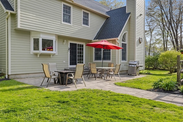 back of property featuring a lawn, a patio, a chimney, and a shingled roof