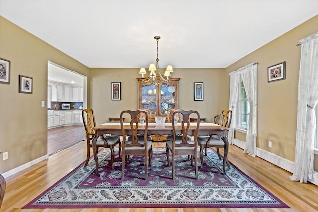 dining room with baseboards, a chandelier, and light wood finished floors