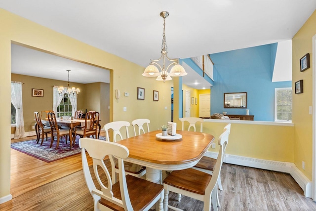 dining space with baseboards, wood finished floors, and a notable chandelier