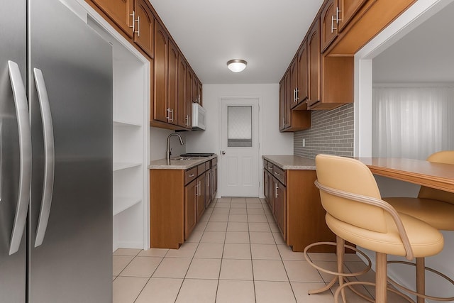 2630 Kingsbridge Ter Unit 2St, Bronx, NY 10463 - kitchen featuring stainless steel fridge, white microwave, light tile patterned floors, a sink, and decorative backsplash