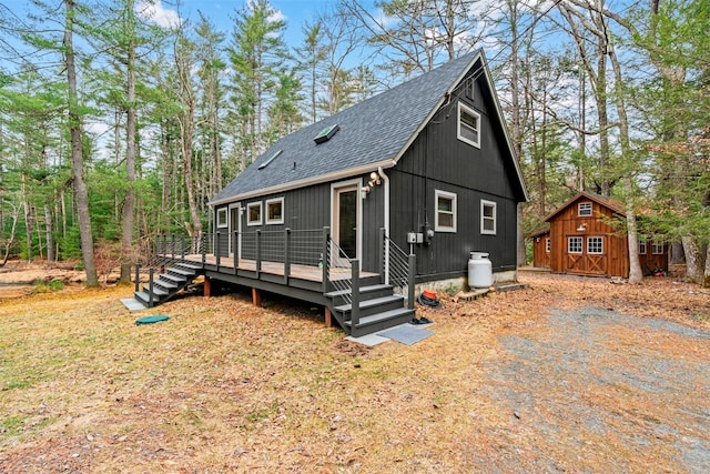 chalet / cabin featuring an outbuilding, a wooden deck, and roof with shingles