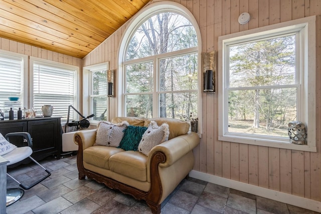 sunroom featuring vaulted ceiling, wood walls, wood ceiling, stone finish flooring, and baseboards