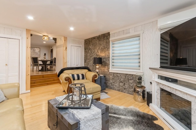 living room featuring wood finished floors, a premium fireplace, and a wall mounted AC