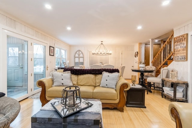 living area featuring stairway, light wood finished floors, wood walls, a chandelier, and recessed lighting