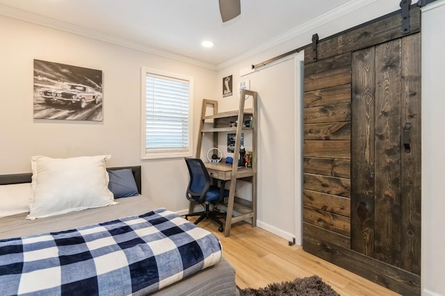 bedroom featuring a barn door, wood finished floors, ornamental molding, baseboards, and recessed lighting