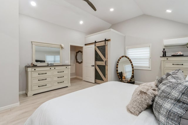 bedroom with a barn door, an AC wall unit, light wood-style flooring, vaulted ceiling, and recessed lighting
