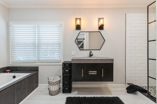 full bathroom featuring crown molding, tiled shower, vanity, tiled bath, and baseboards