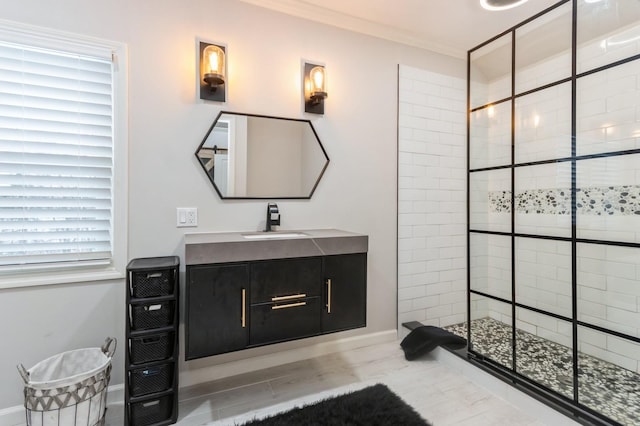 full bathroom featuring a tile shower, vanity, ornamental molding, baseboards, and wood finished floors