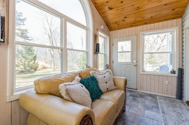sunroom with wooden walls, vaulted ceiling, healthy amount of natural light, wooden ceiling, and stone finish floors