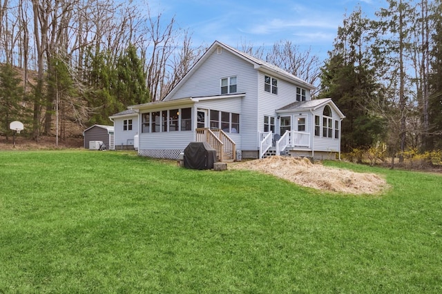 back of property featuring a sunroom, a lawn, and a storage unit