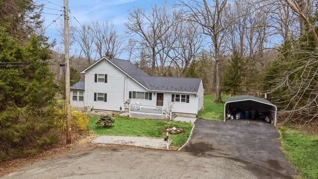 traditional-style home with a carport, asphalt driveway, a front yard, a wooden deck, and roof with shingles