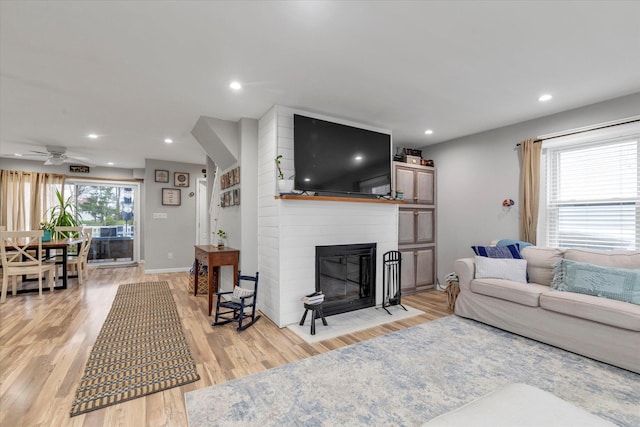 living room featuring a large fireplace, a ceiling fan, recessed lighting, and light wood-type flooring