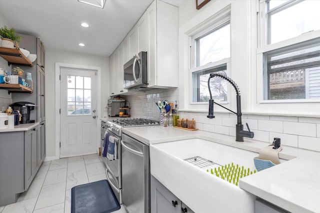 kitchen with gray cabinets, marble finish floor, appliances with stainless steel finishes, and a wealth of natural light
