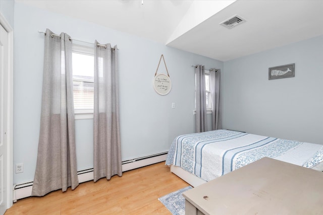 bedroom with light wood finished floors, visible vents, a baseboard heating unit, and baseboard heating