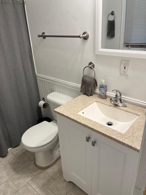 2659 Rte 52, Hopewell Junction, NY 12533 - bathroom with tile patterned floors, toilet, curtained shower, vanity, and wainscoting