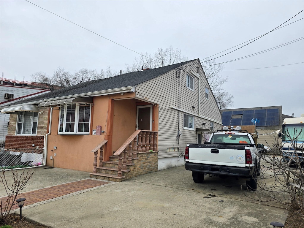 view of front of house with roof with shingles, stucco siding, and concrete driveway