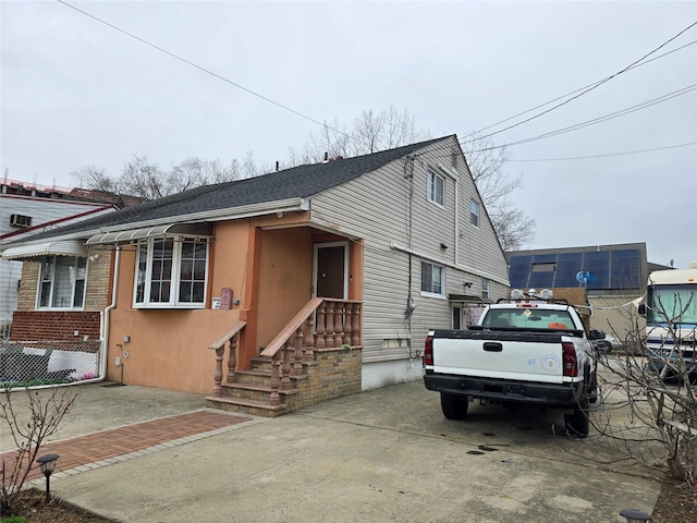 view of front of house with roof with shingles, stucco siding, and concrete driveway