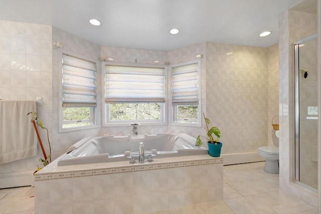 full bathroom featuring a garden tub, tile patterned floors, toilet, and tile walls