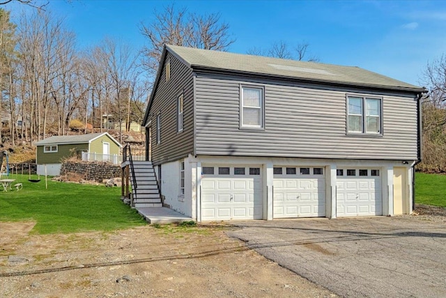 exterior space featuring stairway, aphalt driveway, a yard, and a garage