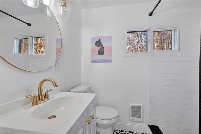 bathroom featuring a wealth of natural light, toilet, tiled shower, and vanity