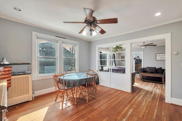 dining room featuring wood finished floors, crown molding, baseboards, and ceiling fan