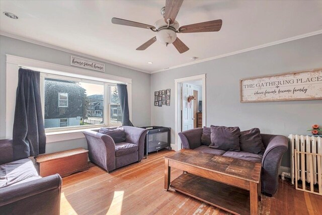 living area with radiator heating unit, crown molding, ceiling fan, and wood finished floors