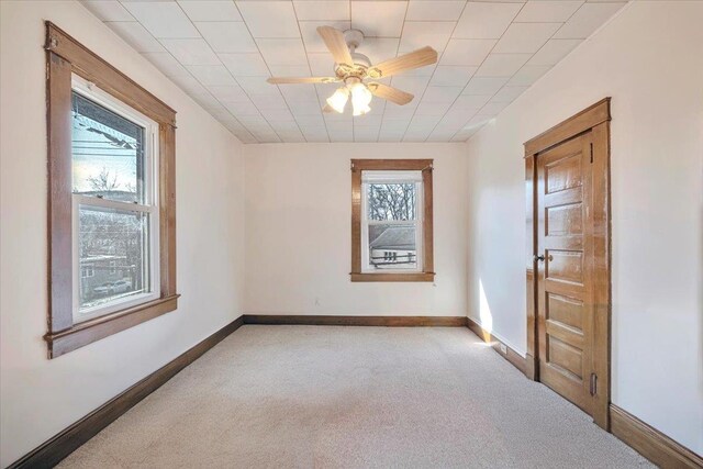 carpeted spare room featuring baseboards and ceiling fan