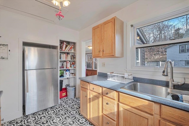 kitchen with light brown cabinets, a sink, and freestanding refrigerator