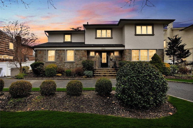 view of front of home with fence, stucco siding, and stone siding