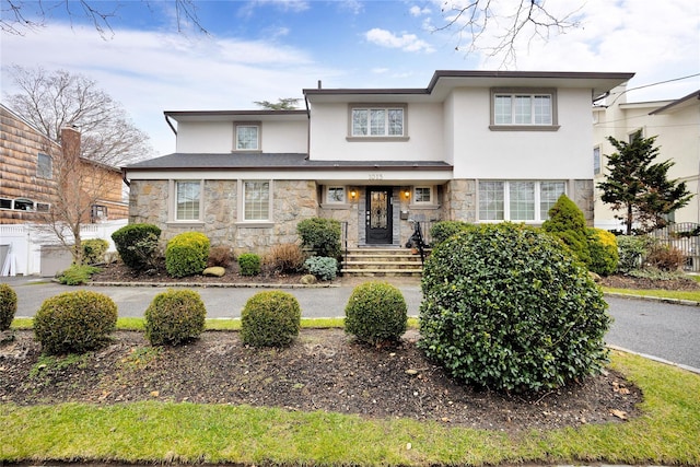 view of front of house with fence, stucco siding, and stone siding