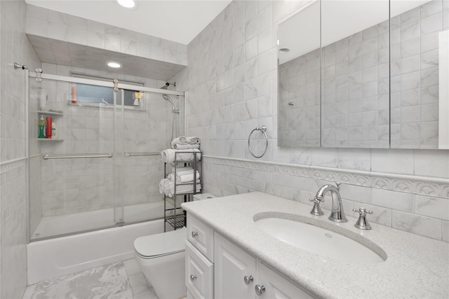 full bathroom featuring tile walls, vanity, combined bath / shower with glass door, toilet, and recessed lighting