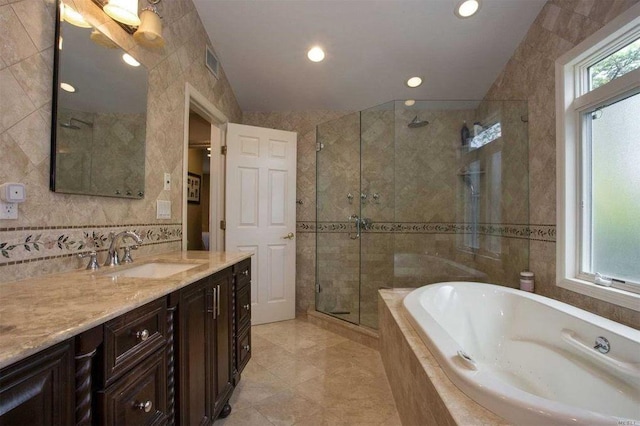 full bath featuring vanity, tile walls, visible vents, a bath, and a stall shower