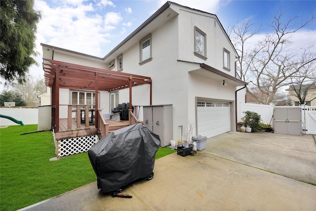 rear view of property featuring a wooden deck, a gate, fence, a yard, and stucco siding