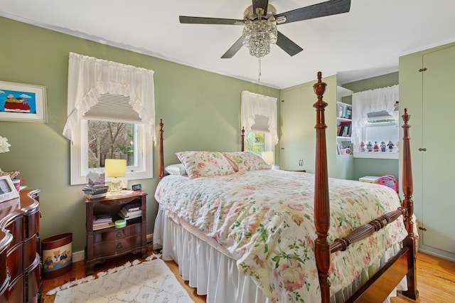 bedroom with baseboards, multiple windows, wood finished floors, and a ceiling fan