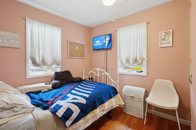 bedroom featuring wood finished floors, baseboards, and multiple windows