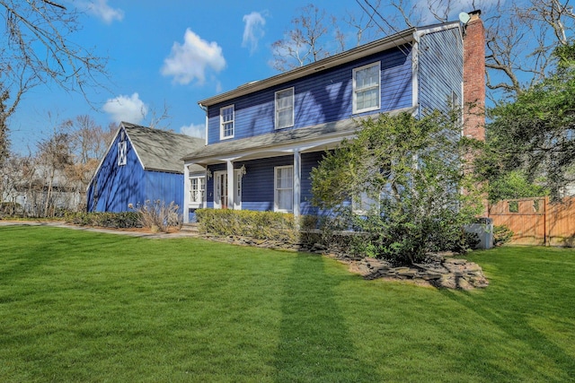 view of front facade featuring a front lawn, a chimney, and fence