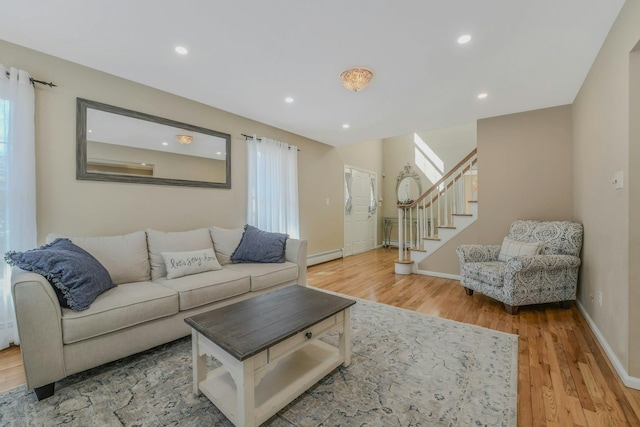 living area featuring a baseboard radiator, recessed lighting, light wood finished floors, and stairs