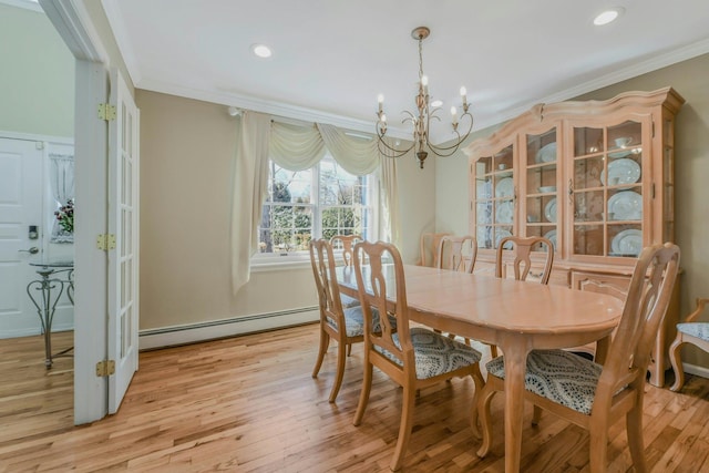 dining space with ornamental molding, a baseboard heating unit, a chandelier, and light wood finished floors