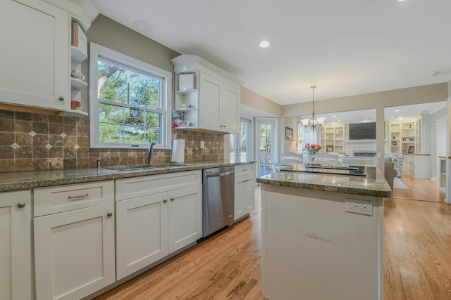 kitchen featuring appliances with stainless steel finishes, white cabinetry, a sink, open shelves, and a center island