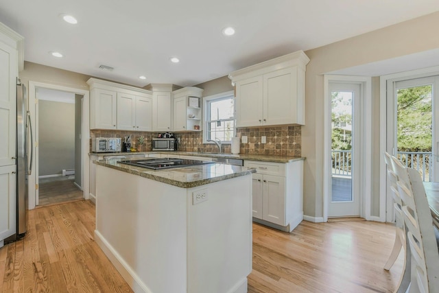 kitchen with white cabinets, stone counters, appliances with stainless steel finishes, and decorative backsplash